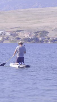 Person on sup board kneeling and rowing