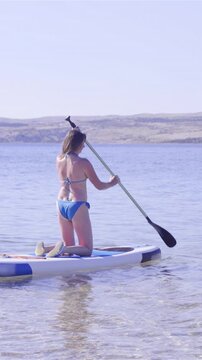 Woman first time rowing on sup while kneeling