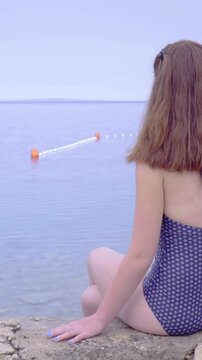 Girl in swimsuit observing boat on sea