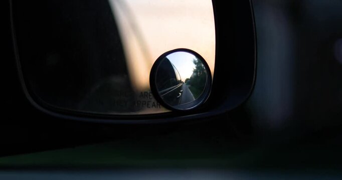 bad evening road with potholes visible through the right side mirror
