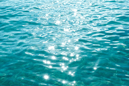 Turquoise ocean water surface background with sun reflection, soft focus