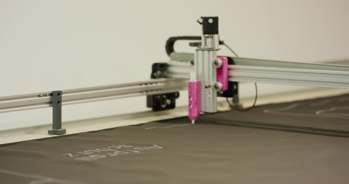Automated machine precision head drawing pattern on dark material in workshop