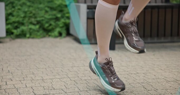 Young beautiful woman athlete in sportswear training and jumping rope in an urban park among high-rise buildings and trees - legs in close-up