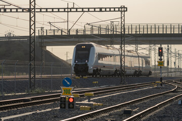 Commuter passenger train traveling on railway infrastructure during golden hour. © edufoto.es