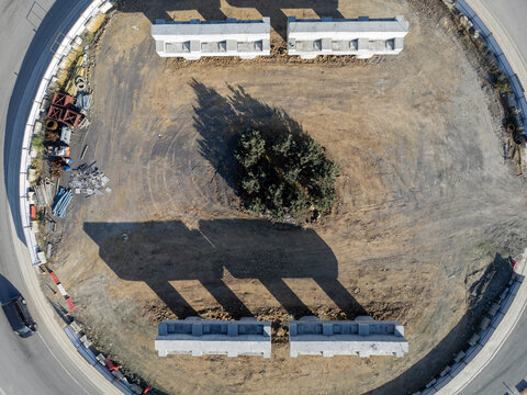Aerial view of a construction site with concrete segments arranged in a circle around central trees, casting long shadows on dry ground in Istanbul, Istanbul, Turkiye.