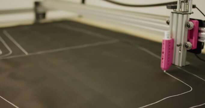 Industrial machine head drawing technical pattern on fabric sheet in workshop