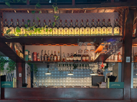 Kyiv, Ukraine - March 21, 2026: Jameson whiskey bottles sit on a wooden bar shelf with hanging glass racks and warm ambient lighting in a cozy pub setting for social nightlife drinks
