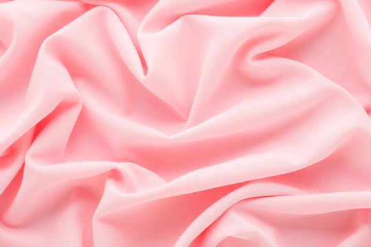 Pastel light pink soft wrinkled gabardine elastane fabric background. Closeup. Top down view.