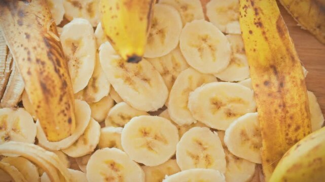 Fresh sliced bananas are neatly arranged on the kitchen counter next to their peeled peels, ready for smoothies, desserts, or baked goods. The concept of healthy food and proper nutrition