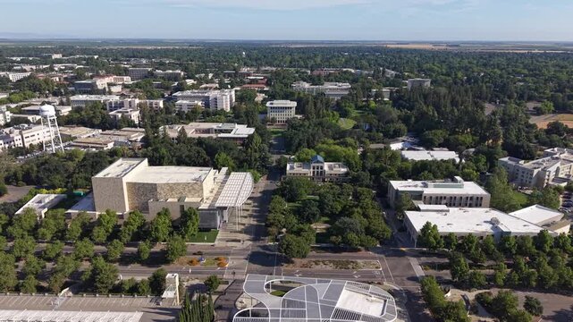 Panning drone view showcasing the University of California Davis campus with modern architecture, leafy streets, and tree-filled landscapes in crisp, natural morning light. Perfect aerial footage.