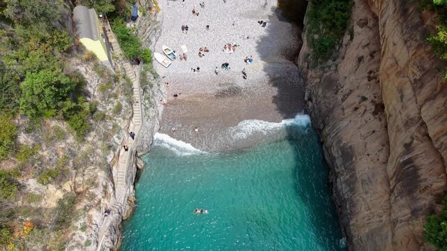 Aerial Drone Top View of Fiordo di Furore Secret Beach with People Swimming in Turquoise Water and Rocky Canyon Walls, Amalfi Coast Italy