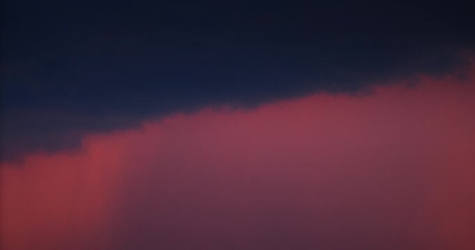 Dramatic red sunset sky featuring heavy dark raHeavy rain clouds rolling in during dramatic red sunset timelapse.in clouds and climate change concept.