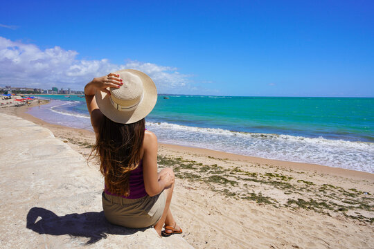 Young woman sitting enjoying view of Pajucara beach, Maceio, Brazil