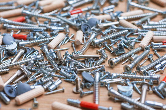 Furniture assembly hardware, screws, dowels, cam locks and fasteners on a wooden surface. DIY woodworking, cabinet installation, home improvement, carpentry supplies and furniture manufacturing.