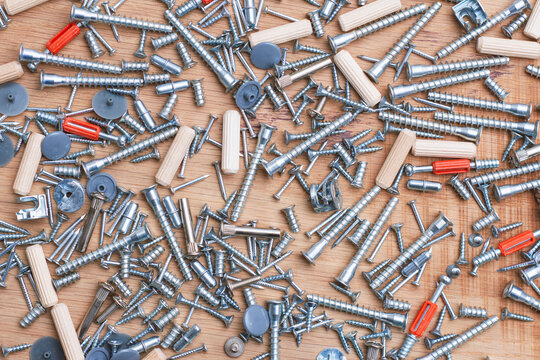 Furniture assembly hardware, screws, dowels, cam locks and fasteners on a wooden surface. DIY woodworking, cabinet installation, home improvement, carpentry supplies and furniture manufacturing.