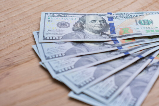 US dollar banknotes, one hundred dollar bills on a wooden surface with copy space. Finance, cash payment, personal savings, investment, banking, wealth and money management concept for business use.
