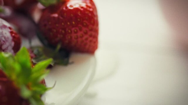 Ripe strawberries with distinct texture and seeds lie in a bowl drizzled with cream. An idea for an exquisite treat using fresh berries with a milky filling