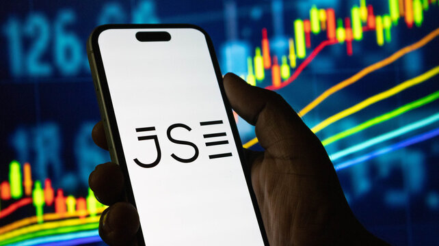 Johannesburg stock exchange (JSE) logo on smartphone screen with financial graphs in background.