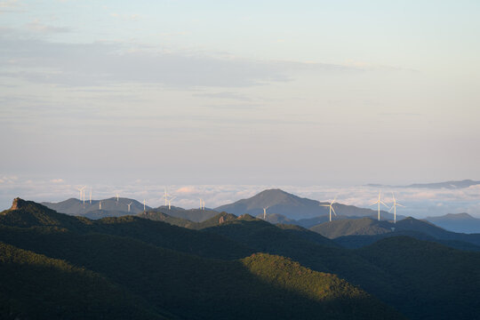Wind Turbine Farm on a Forested Mountain Ridge at Sunrise. Wind turbines generate clean renewable energy.	