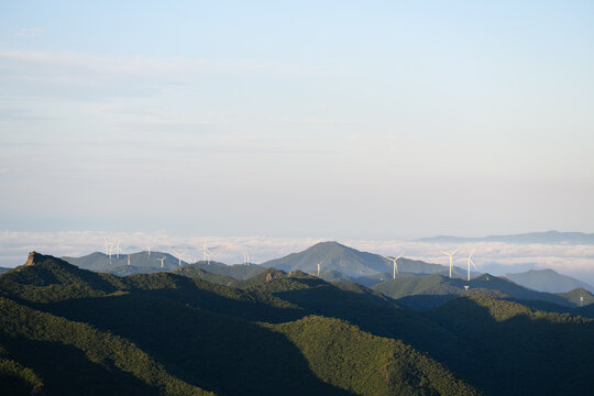 Wind Turbine Farm on a Forested Mountain Ridge at Golden Hour. Wind turbines generate clean renewable energy.	