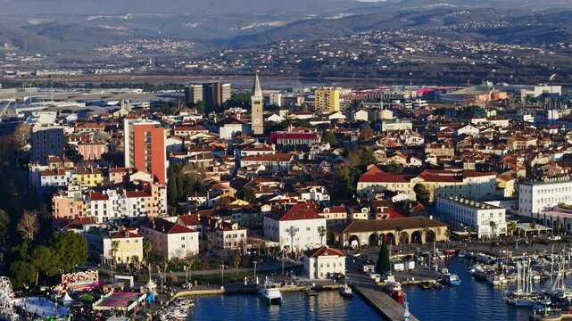 View of Kopers waterfront with boats in marina and city buildings along the shore under bright sky.
