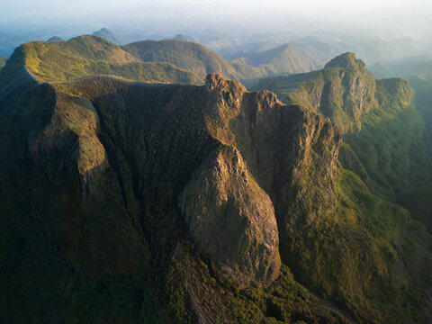 Aerial view of Mount Kelud showing its rugged volcanic crater and steep rocky slopes covered in lush vegetation in Garum, East Java, Indonesia.