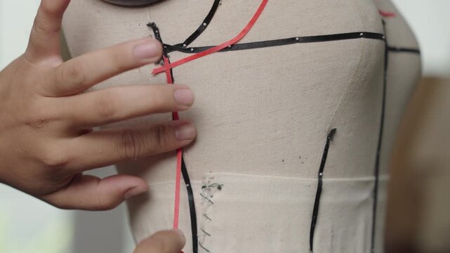 Close-up of marking garment construction lines with style tape on dress form for bridal couture design
