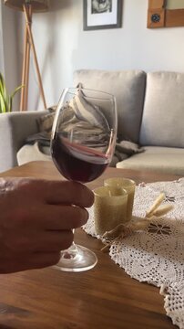 Hand-swirling a glass of red wine in a cosy living room is a way to experience the aroma and flavour of the beverage