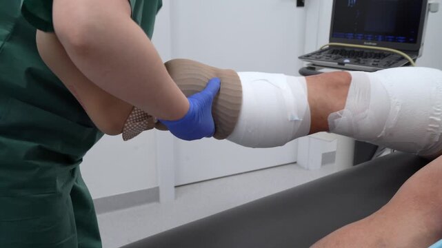 the nurse puts a compression stocking on the patient - after varicose vein surgery