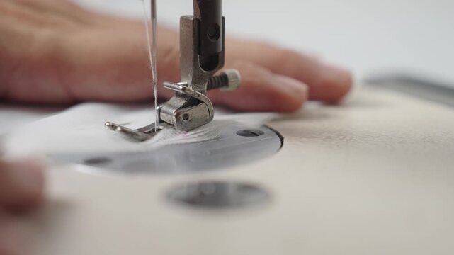 Macro close-up of sewing machine needle stitching wedding dress fabric