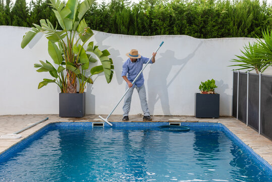 Pool maintenance worker brushing swimming pool tile walls