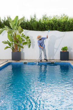 Vertical pool maintenance worker brushing swimming pool tile walls