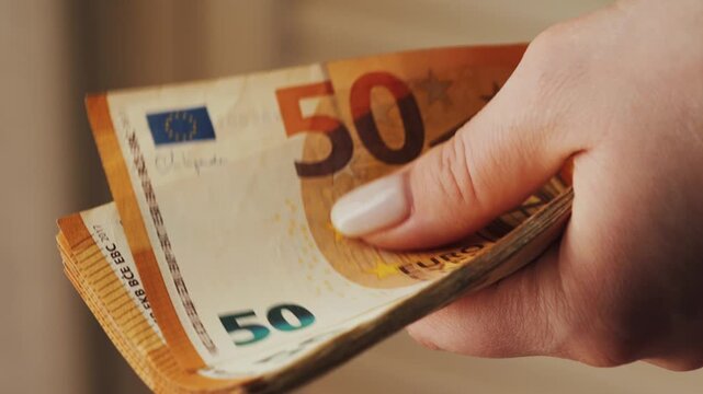 A woman counts a 50-euro note. Close-up of a hand counting a stack of bills. High quality 4k footage