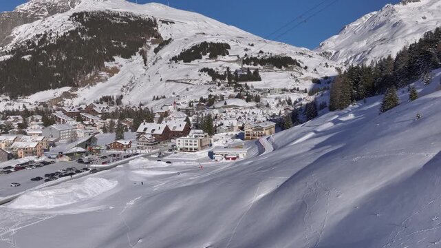 Andermatt, Switzerland in Winter. Aerial of mountain village in Swiss alps in Canton Uri on sunny day after snow fall. 