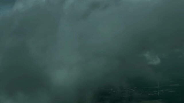 Moody and dramatic aerial shot of a plane cruising through heavy overcast grey clouds
