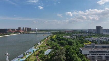 Fototapeta premium Shouguang Mi River waterfront park with modern buildings and green pathways under clear blue sky