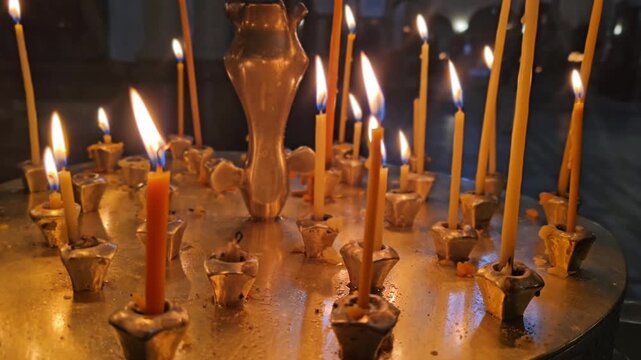 Candles burn in a church as worshippers light candles and offer prayers during a quiet moment of reflection at a local religious site
