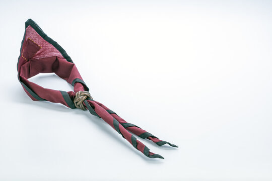 Authentic Thai boy scout neckerchief in deep maroon red fabric with dark green border edging secured by a handcrafted leather Turk's head woggle knot displayed on a clean white studio background