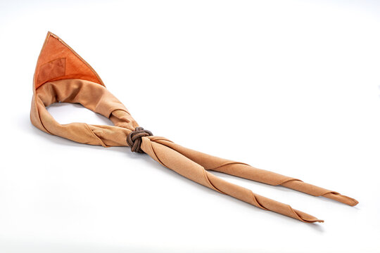 Traditional Thai Boy Scout neckerchief in tan brown cotton fabric secured with handmade leather Turk's Head woggle knot, isolated on clean white studio background showing scouting uniform