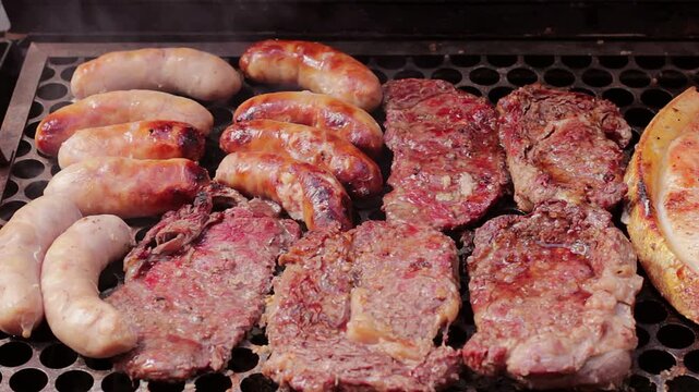 A variety of beef steaks and chicken sausages grilling on a hot barbecue, amidst the smoke