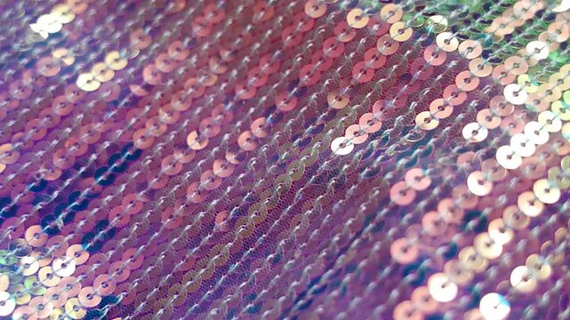Shimmering iridescent sequin fabric sparkling in soft light with gentle movement. Glamorous abstract background and luxury celebration concept.