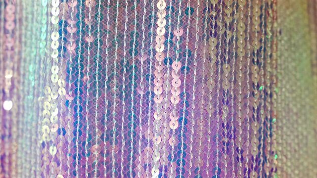 Shimmering iridescent sequin fabric sparkling in soft light with gentle movement. Glamorous abstract background and luxury celebration concept.