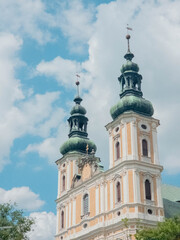 Fototapeta premium Tall church towers rise into the blue sky with fluffy clouds above.Church pw. St. Apostolow Piotra i Pawla w Nysie