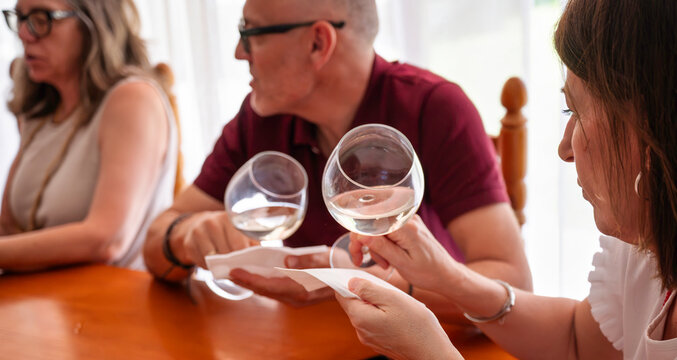 Adult students examining the color and clarity of white wine in a glass during a guided wine tasting workshop with a professional wine educator