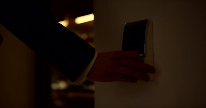 Person swiping a keycard on a wall mounted electronic scanner to unlock a commercial glass door