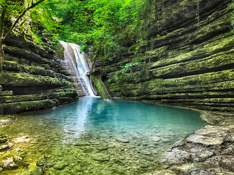 The image shows the horizontal rock formations (stepped structure), the turquoise pool where the water cascades, and the dense green vegetation surrounding the Tatlıca Waterfalls in Erfelek, Sinop.