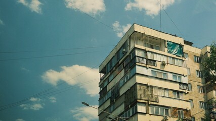 Modern apartment building facade against a blue sky with clouds. Ideal for architecture, real estate, residential development, and urban lifestyle concepts. © Aida