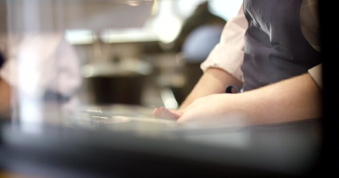 Close-up of a chef using a knife to slice a piece of raw meat on a counter