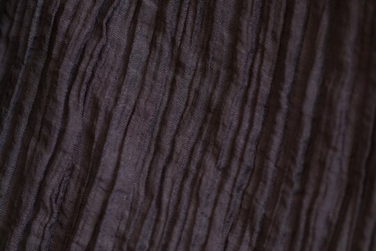 Macro shot of brown pleated and crinkled lyocell polyamide blend fabric texture. Detailed woven pattern and synthetic fiber structure with beautiful soft bokeh