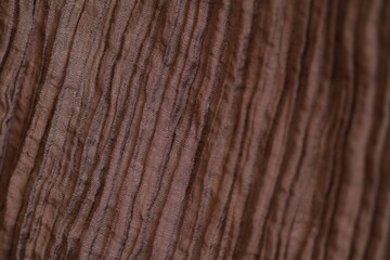 Obraz premium Macro shot of brown pleated and crinkled lyocell polyamide blend fabric texture. Detailed woven pattern and synthetic fiber structure with beautiful soft bokeh
